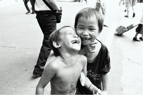 Two young children laughing together — community served by Pararthya SDECS