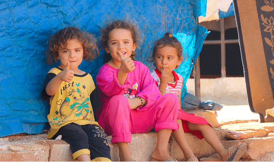 Three young girls smiling together at a Pararthya SDECS education camp