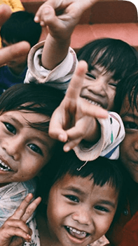 Children smiling and showing peace signs at a Pararthya community event
