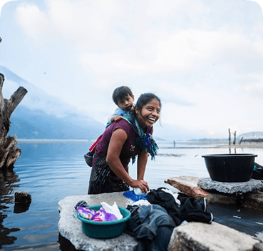 A girl washing clothes by a lake during a Pararthya outreach program